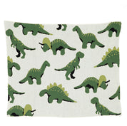 The in2green Baby Dinosaur Blanket is made of white recycled cotton and showcases charming green dinosaur patterns, including playful Stegosaurus and T. rex in various poses.