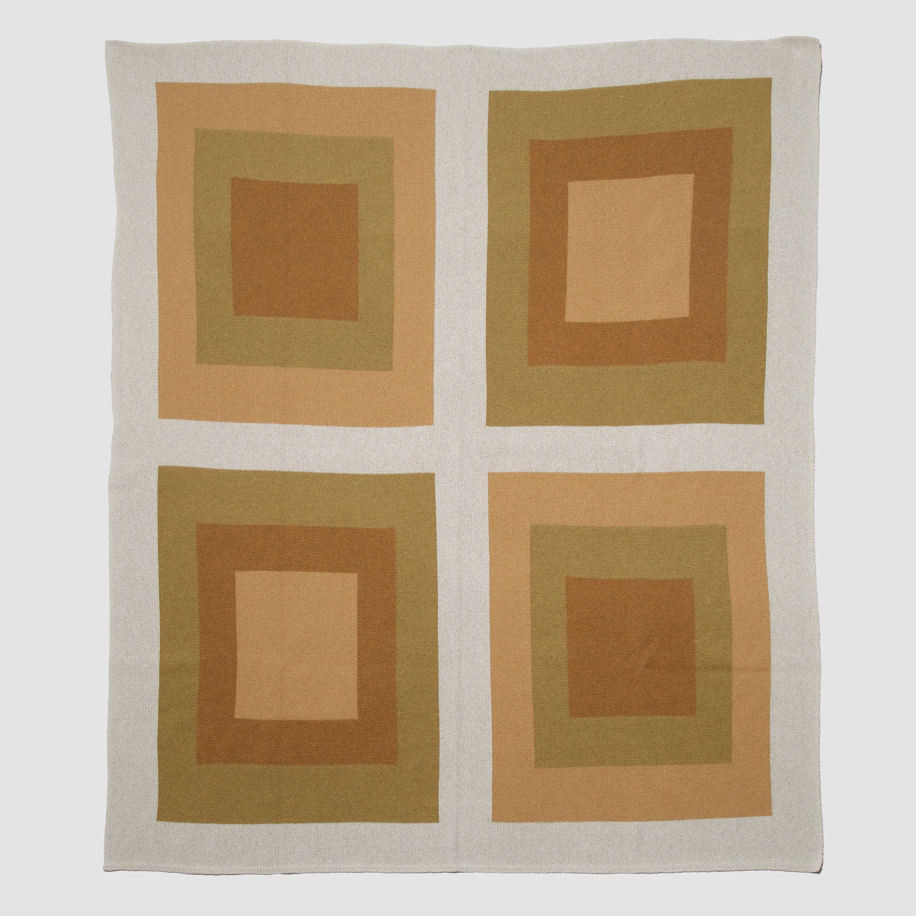 The in2green Bauhaus Throw Blanket showcases a classic Bauhaus design with four squares, each containing nested rectangles in warm brown and tan tones.