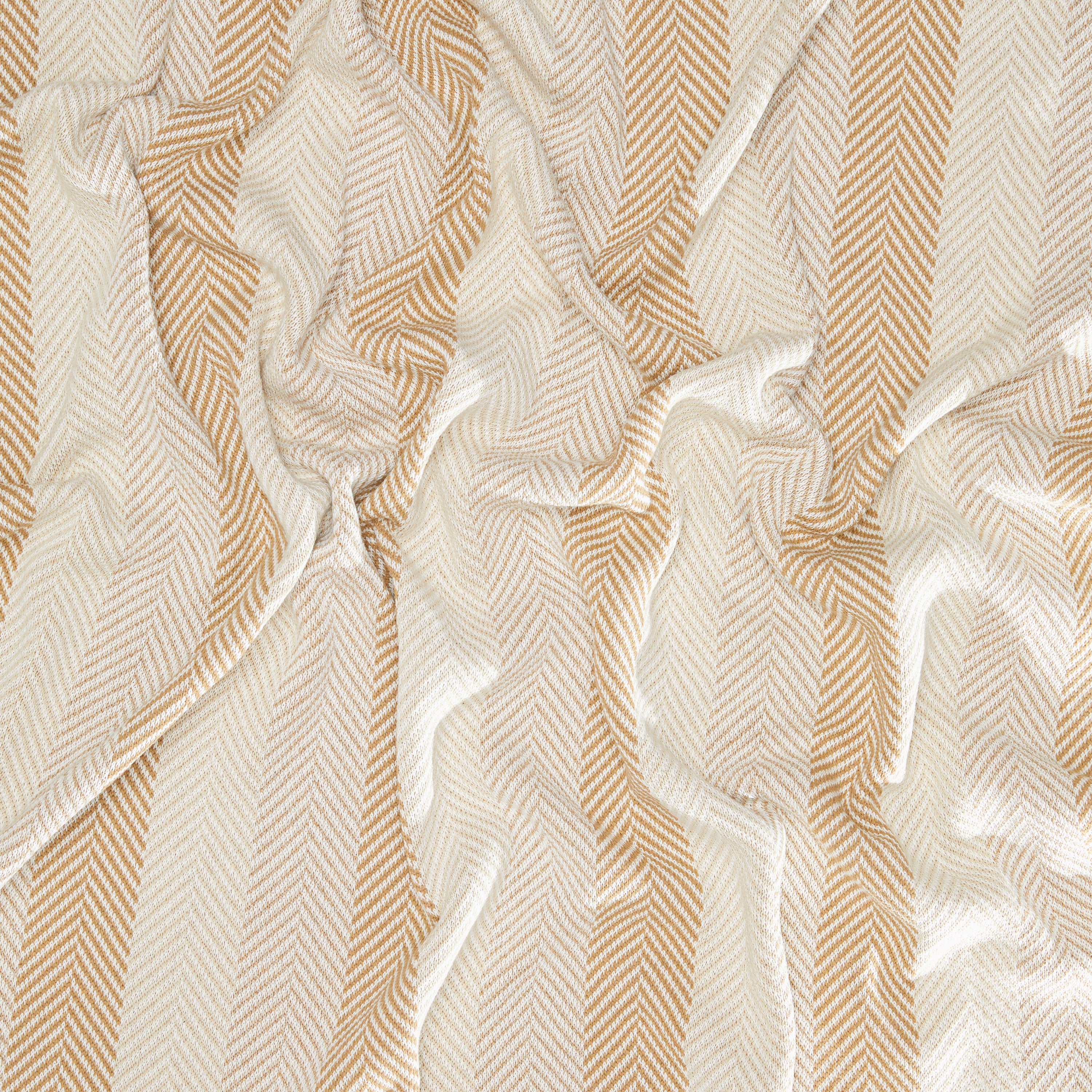 The Herringbone Hues Throw Blanket by In2Green showcases a herringbone pattern with vertical stripes in beige and white. Made from recycled cotton, its charmingly wrinkled texture combines style and sustainability, proudly crafted in the USA.