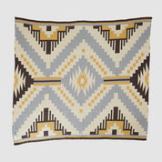 Introducing the New Horizon Throw Blanket by in2green, showcasing Southwestern-inspired geometric patterns with zigzag and diamond designs. Crafted from recycled cotton, it features a harmonious blend of beige, brown, yellow, and gray tones.