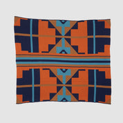 Introducing the Sun Rise Throw Blanket by in2green, a square wool throw featuring a bold geometric design in orange, blue, black, and brown on a crisp white backdrop. Made with care from recycled cotton yarns, this eco-friendly creation brings warmth and style to any space.