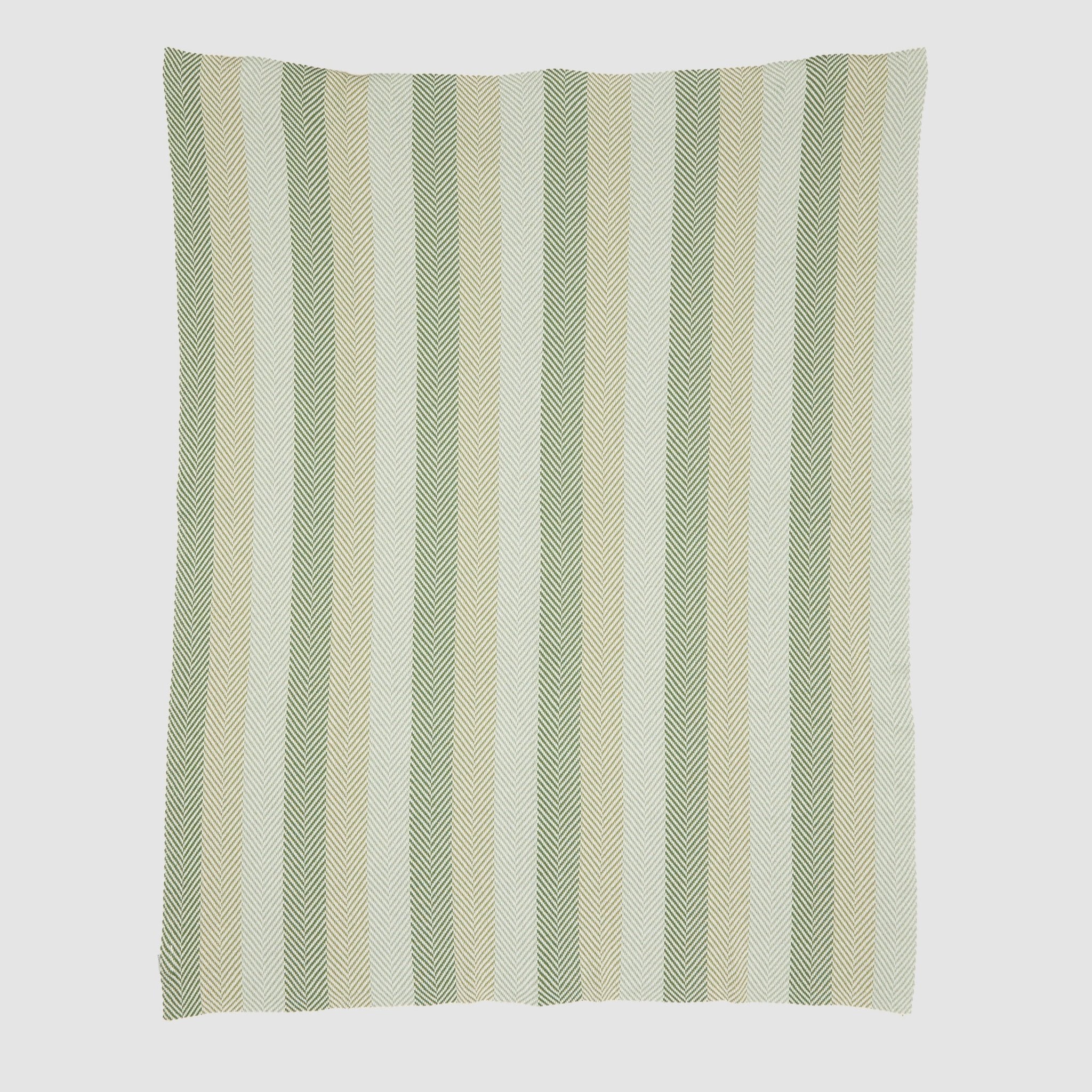 The Herringbone Hues Throw Blanket by In2Green is made in the USA from recycled cotton, featuring a white background with patterned vertical stripes in green, beige, and light gray.