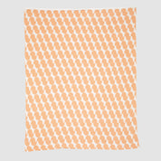 The Poly Juki Throw Blanket by Petra Kaksonen from in2green features an orange and white abstract pattern made from recycled polyester, displayed on a plain background.