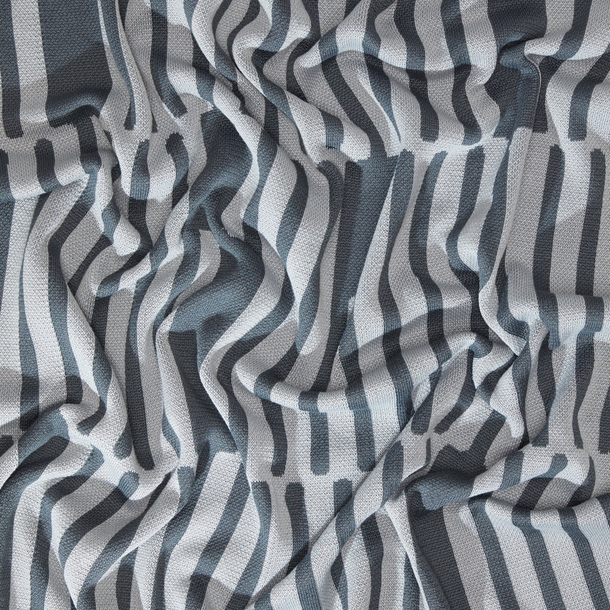 The Poly Retki Throw Blanket by Petra Kaksonen in charcoal and light grey.